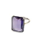 A chunky design dress ring, set with rectangular cut purple coloured paste stone, in a white metal