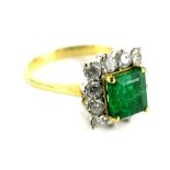An 18ct gold emerald and diamond cluster ring, set with a rectangular cut pale green emerald, 6mm