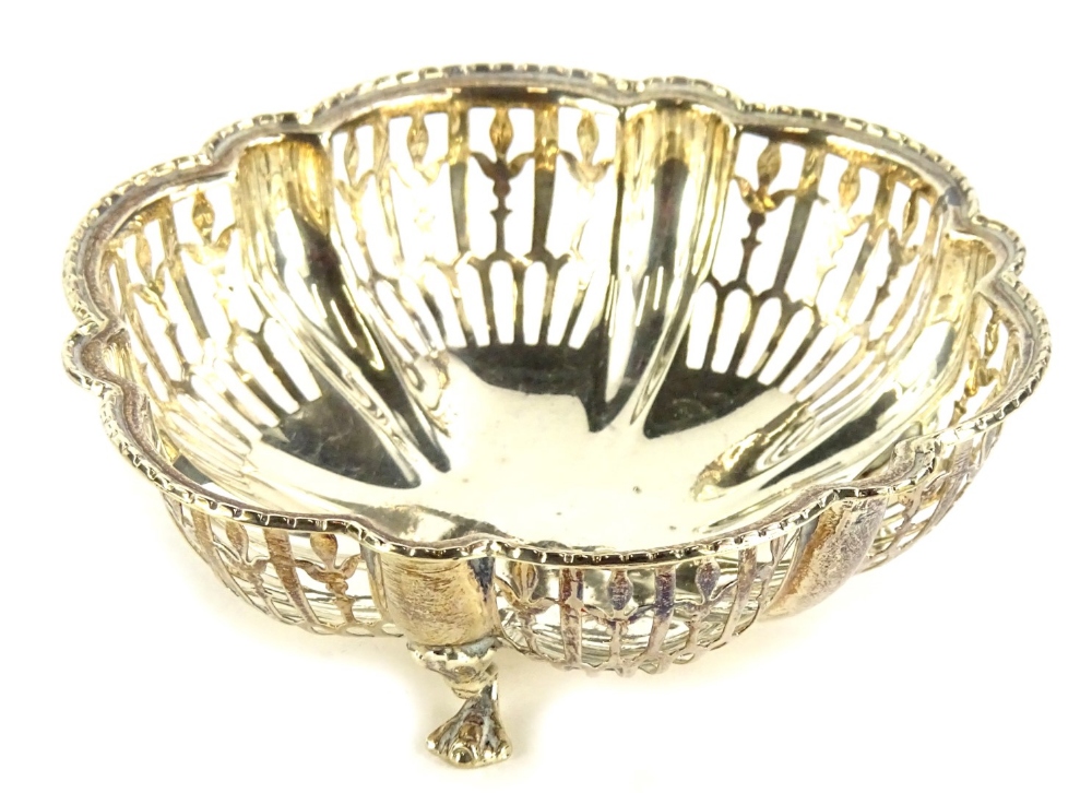 A George V silver dish, of floral form, with pierced sides and plain centre, on squat triple hoof