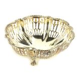 A George V silver dish, of floral form, with pierced sides and plain centre, on squat triple hoof