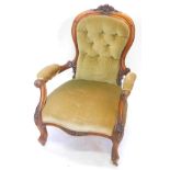 A Victorian walnut showframe armchair, upholstered in buttoned green dralon, the frame carved with