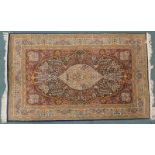 A Persian rug, with a central oval medallion, all over floral design, on a dark ground, with red