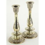 A pair of white metal candlesticks, each with geometric dish holders, baluster stems and stepped