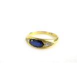 An 18ct gold sapphire and diamond gypsy ring, with elongated oval cut synthetic sapphire, flanked by