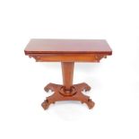 A Regency mahogany fold over card table, with a green baize interior, raised on a tapering octagonal