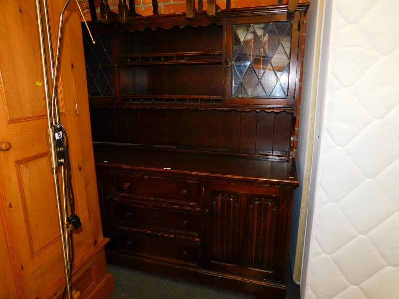 An oak kitchen dresser, with two glazed doors, open shelves above two linen fold carved doors and