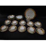 A Limoges porcelain part tea service, printed with floral reserves within a gilt band, comprising