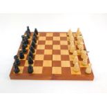 A Polish late 20thC carved wooden chess set, with board box, 30cm wide.