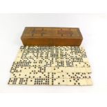 A wooden cribbage board, containing nine dot bone and ebony dominoes.