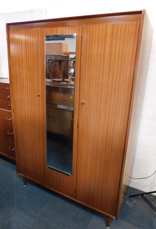 A Nathan teak double wardrobe, with a central mirrored section flanked by two doors, raised on