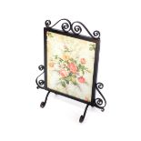 A cast iron and fabric fire screen, printed with flowers, 77cm high, 65cm wide.