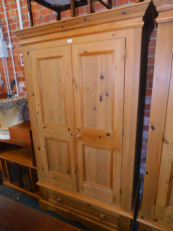 A pine double wardrobe, with panelled doors and lower drawer, 198cm high, 116cm wide, 61cm deep.