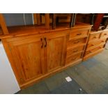 A pine dresser base, with curved end, below two cupboard doors with flight of four drawers, raised