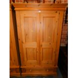A pine double wardrobe, with panelled doors and lower drawer, 198cm high, 116cm wide, 61cm deep.