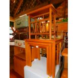 A teak effect nest of tables, 46cm high, 54cm wide, 39cm deep., together with a teak magazine rack