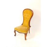 A Victorian mahogany balloon back nursing chair, upholstered in yellow draylon, raised on cabriole