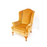 A Queen Anne style wing armchair, upholstered in brown draylon, raised on cabriole legs.