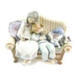 A Lladro porcelain figure group, modelled as two girls seated on a sofa, one reading together with