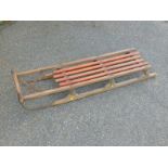 A pine sledge with red slats, 110cm long.