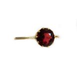 A ladies solitaire dress ring, claw set with a garnet on a plain shank, marked 9ct, size N, 2g all