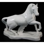 A Portuguese plain pottery model of a standing horse, with foot raised on shaped base, marked