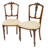 A pair of Edwardian walnut stained salon chairs, each with shaped cresting rails, pierced vertical