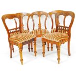 Four very similar Victorian mahogany dining chairs, each with shaped cresting rails, vertical carved