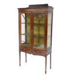 An Edwardian mahogany and boxwood strung display cabinet, with fixed cornice raised above two