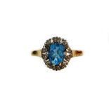 A dress ring, with oval claw set aquamarine coloured section surrounded by small diamonds in an