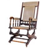 A late 19thC rocking chair, with overstuffed back, arms and serpentine seat, on a scroll base,