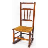 A 19thC elm rush seated rocking chair, with shaped cresting rail above three vertical splats,