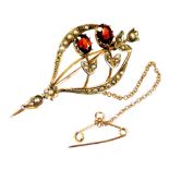An early 20thC brooch, of shaped form set with small florally set seed pearls and two oval red