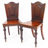 A pair of 19thC oak hall chairs, each with shaped partially carved backs, canted seats and turned