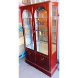 A glazed display cabinet, with arched doors, 161cm high.