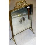 An early 20thC brass firescreen, with bevel glass centred by a flower with heart shaped handle, 70cm