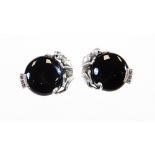 A pair of art 1880 ear studs, each surmounted by wild cats, on polished black circular centres,