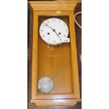 A Comitti light oak wall clock, with instruction manual and warranty.