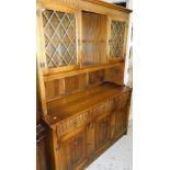 An oak Old Charm style dresser, the upper section with open shelves flanked by glass fronted