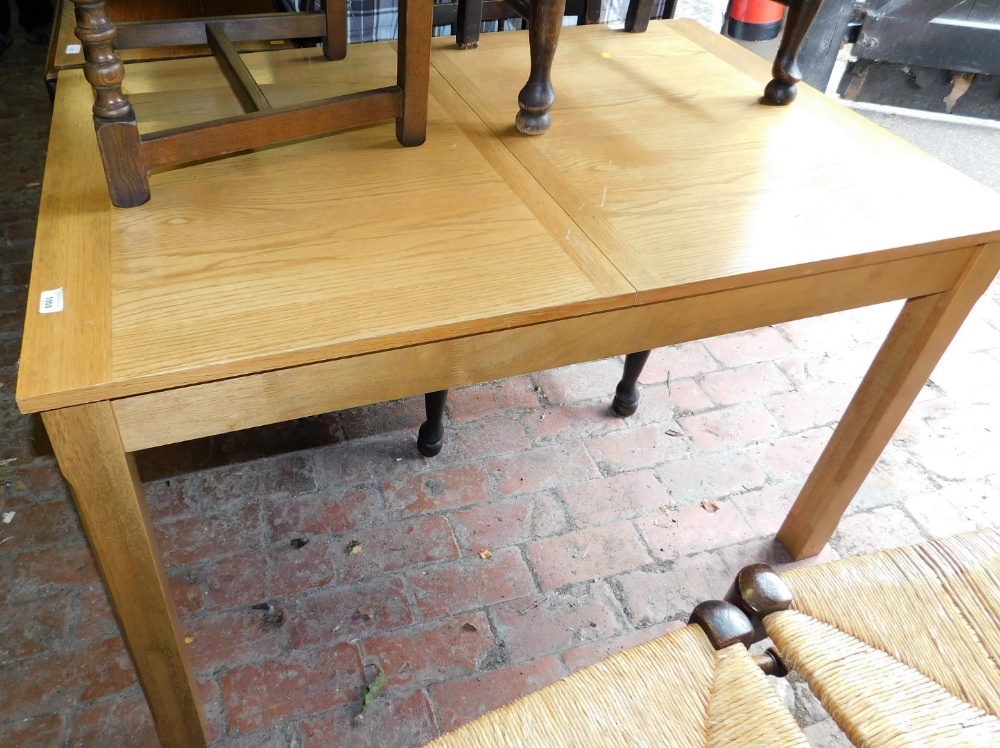 A light oak finish extending dining table, of rectangular form, on heavy block legs, 74cm high,