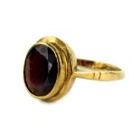 A 9ct gold garnet set dress ring, with oval faceted stone in rub over setting, with etched shoulders