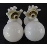 An unusual pair of ceramic wall lights, each modelled in the form of a hand, with opaque globe
