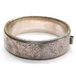 A hinged bangle, with foliate scroll decoration on one side and outer border, with single lion