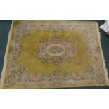 A Chinese cut wool carpet, with a central beige and coloured floral medallion, on a yellow ground,