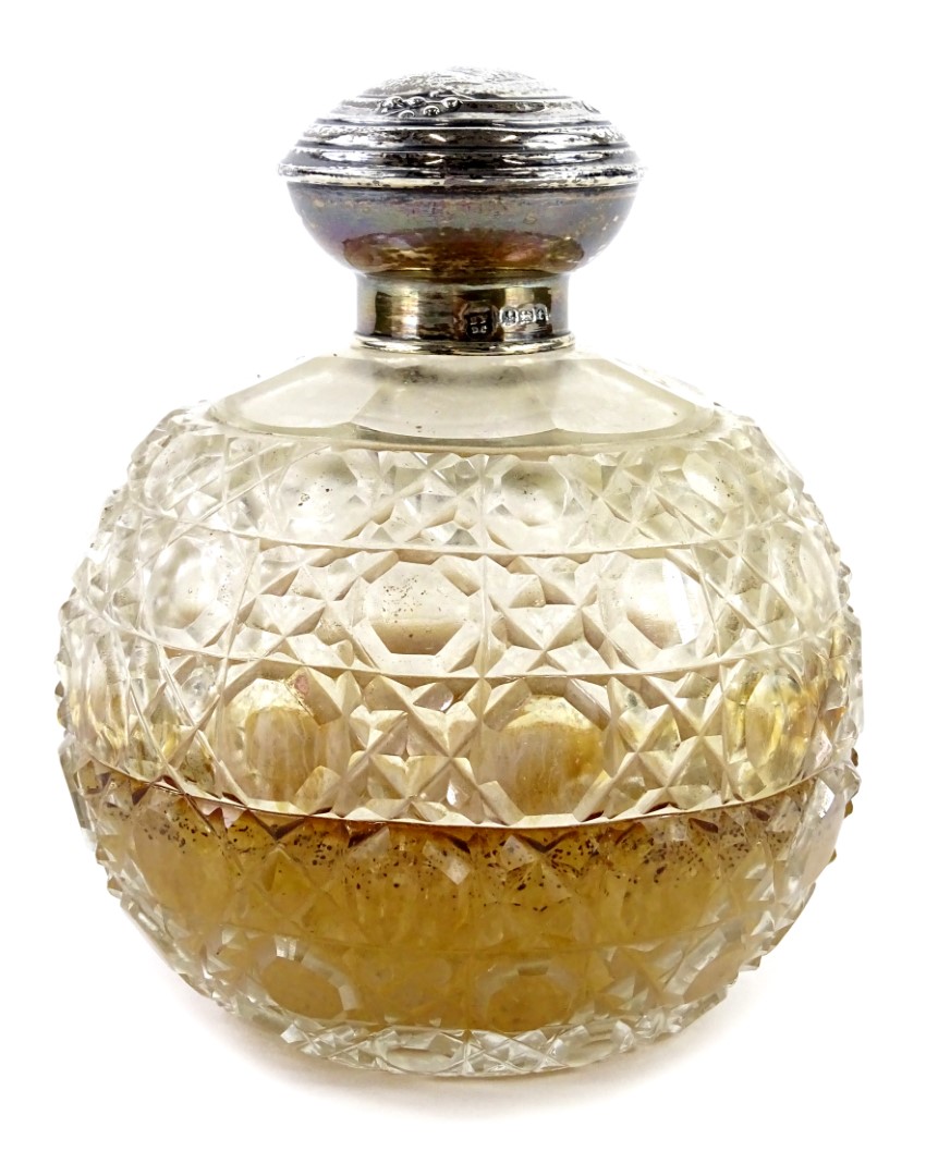 A George V cut glass globular scent bottle, with silver collar and top, the top cast with berries