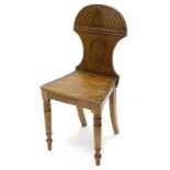 An early 19thC mahogany hall chair, the shaped back, solid seat, on turned tapering legs.