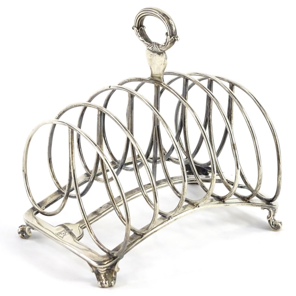 A George IV silver six division toast rack, with reeded and scroll cast handle, concave base and