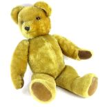 A large plush teddy bear, with velvet pads, bell to one ear, 67cm long overall. Provenance: The