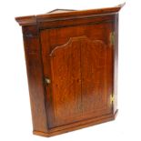 A late 18th/early 19thC oak hanging corner cabinet, with a moulded cornice above a raised panelled