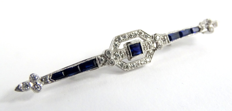 An Art Deco sapphire & diamond bar brooch, set with central square cut blue sapphire 3mm x 3mm,