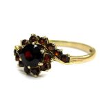 A 9ct gold garnet set dress ring, of twist design with large central stone, flanked by smaller stone